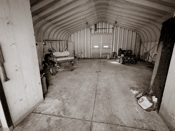 Inside Quonset hut with golf cart and mower.