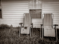 Two chairs against a outbuilding.